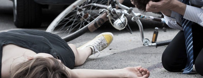 DUI manslaughter vehicle homicide |image: Woman injured lays in street with crashed bike and car nearby. Alavi & Pozzuto are compassionate trial attorneys who can help.